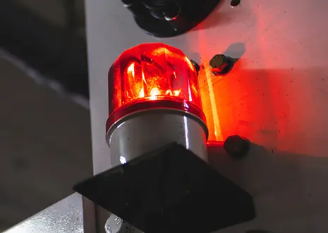 The picture shows a red warning light in an industrial environment.