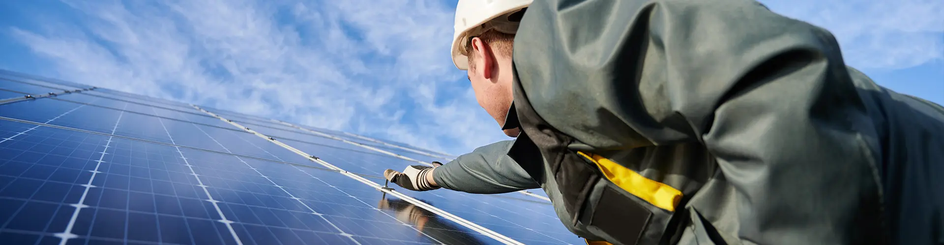 Das Bild illustriert den Prozess, bei dem ein Fachmann für Photovoltaikanlagen eine solche Anlage auf einem Dach installiert.