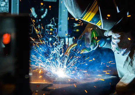 The image illustrates a scene in which a person is performing welding work in an industrial environment.